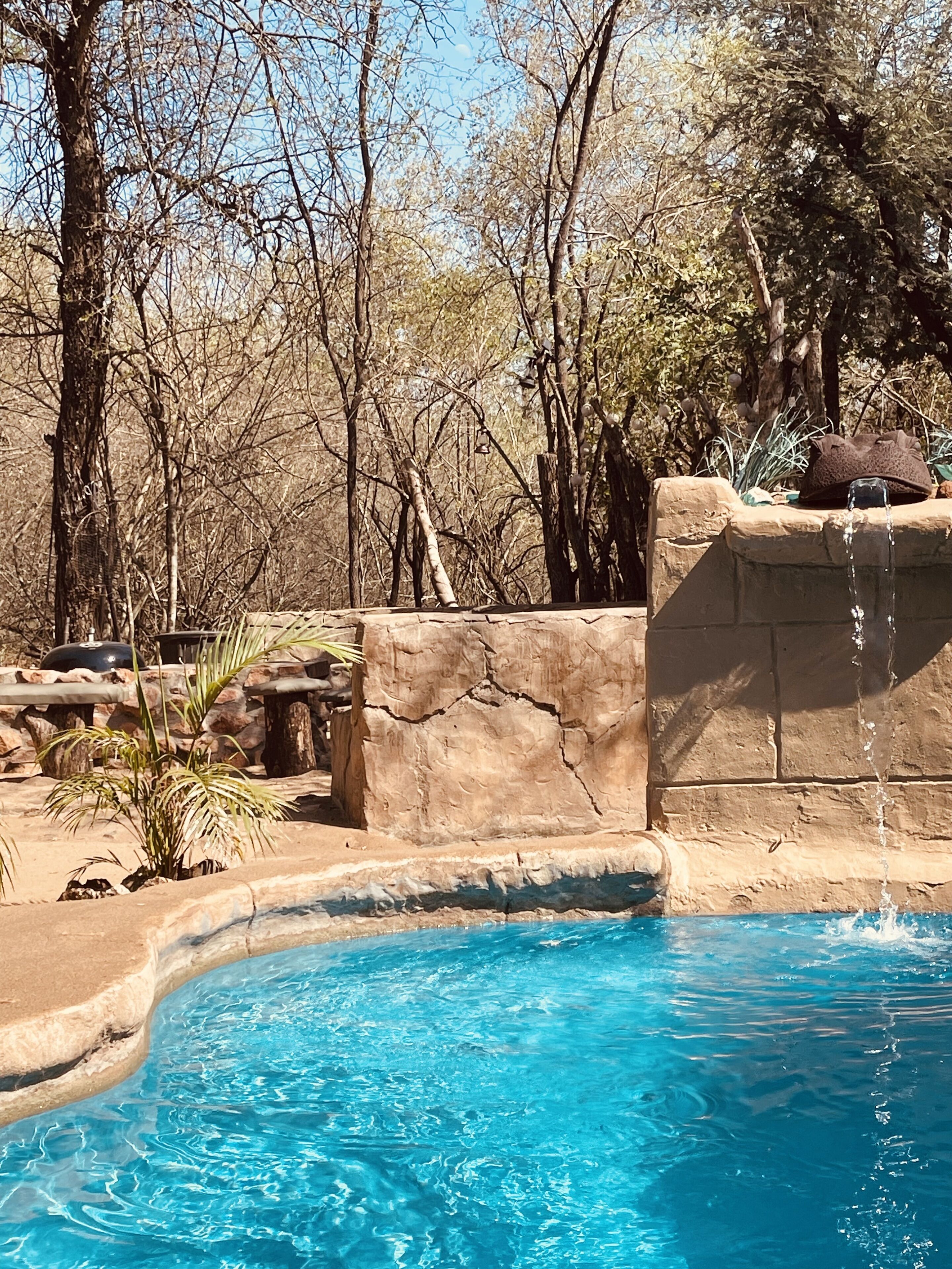 Uma piscina com água azul cristalina, cercada por terreno rochoso e vegetação rasteira.