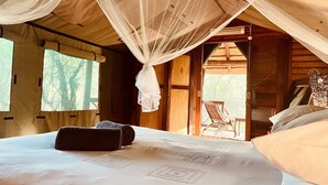 A room with a bed, a chair, and a view of the outdoors. - Nyala Luxury Safari Tents (Nkomazi)
