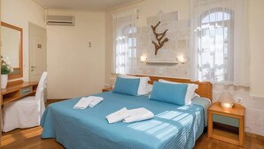 A hotel room with a bed, a desk, a chair, a nightstand, and a wall-mounted air conditioner. - Argo Luxury Villa (Iason Villas), 3 Bedrooms (Maleme)