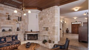 A cozy living room with a stone fireplace, wooden furniture, and decorative items. - Natali Luxury Villa (Iason Villas), 9 Bedrooms (Chania)