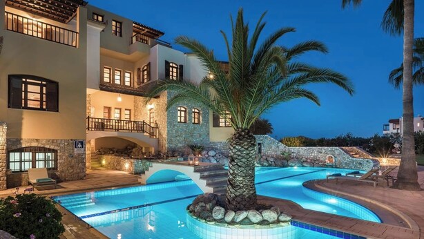 A multi-story hotel with a swimming pool, stone walls, and a palm tree. - Natali Luxury Villa (Iason Villas), 9 Bedrooms (Chania)