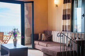 A balcony with a sofa, a table, and a vase of flowers.