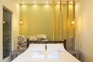 A hotel room with a bed, two bedside tables, a stone wall, and wooden pillars.