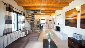 Un salon comprenant un canapé, une table avec un vase, une cheminée et un escalier menant à une autre pièce.