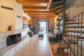A spacious living area with a fireplace, a television, and a staircase leading to an upper floor. - Villa Cretan View with Heated Swimming Pool (Patima)