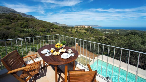 Une terrasse avec une table dressée pour le dîner, offrant une vue sur un paysage montagneux et une piscine.