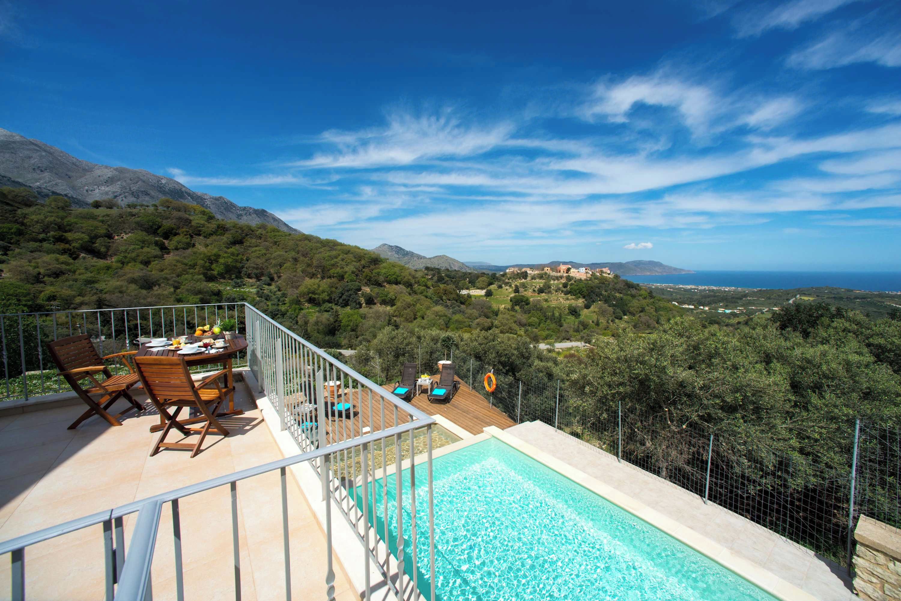 A poolside area with a view of the sea and mountains.