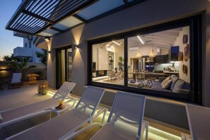 Relax in style on the spacious outdoor terrace with comfortable lounge chairs and a pergola overhead.