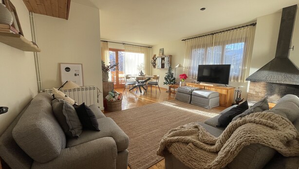 Una sala de estar con chimenea, televisor y comedor con un árbol de Navidad.