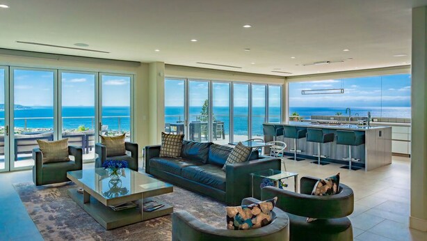 A spacious living area with a large window overlooking the sea, a modern kitchen, and comfortable seating. - La Jolla Dream Stay: Ocean, Bay, Pool (San Diego)