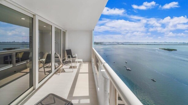 A balcony with a view of the sea and a distant pier.