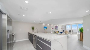 A modern kitchen with a large island, stainless steel appliances, and a view to the living area.