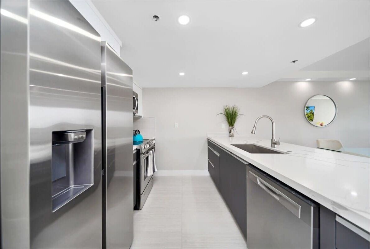 A modern kitchen with stainless steel appliances, a built-in water dispenser, and a sleek countertop.