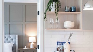 Une chambre d’hôtel moderne équipée d’un lit, d’une table de chevet, d’une lampe et offrant une vue sur la cuisine adjacente.