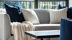 Un salon moderne avec un canapé, une table basse et une vue sur les montagnes, visible à travers une grande fenêtre.
