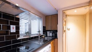 A compact kitchen with a built-in dishwasher, a sink, and wooden cabinets.