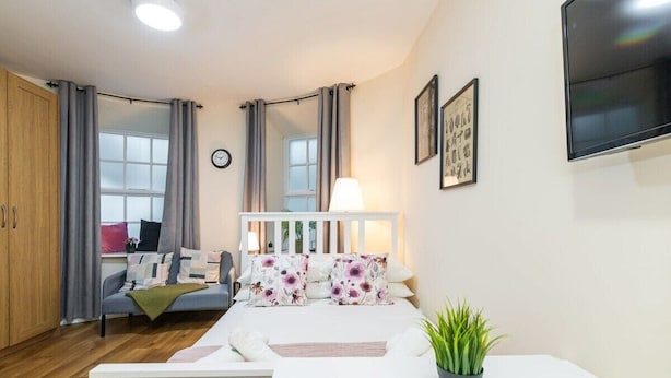 A modern bedroom with a bed, bedside table, and a TV mounted on the wall. - Cosy citycentre flat with TV & Wi-Fi included (Dublin 1)