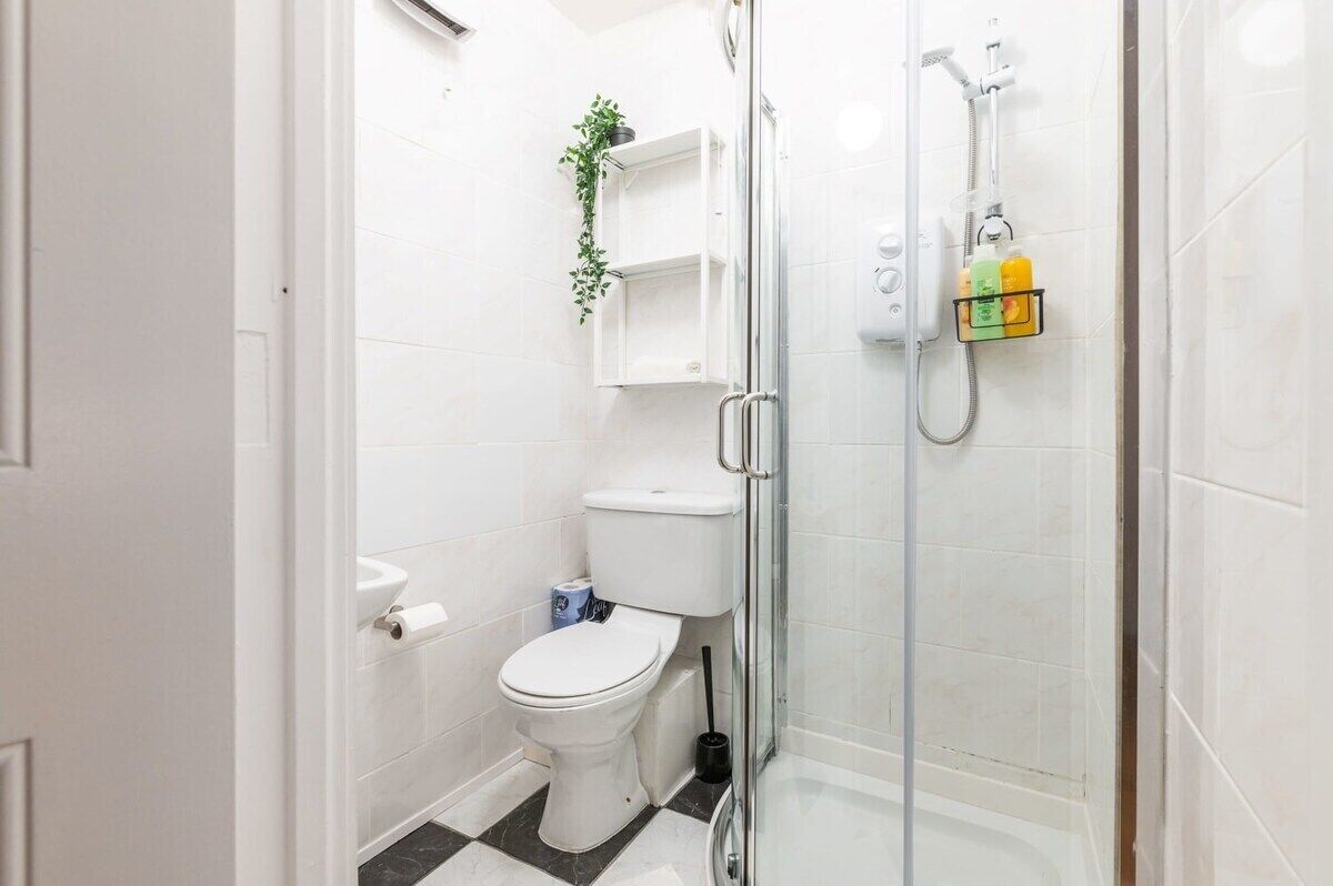 Une salle de bain comprenant des toilettes, une douche et un espace de douche fermé par des parois en verre.