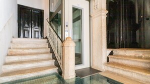 Eine Treppe mit Glasboden, die zu einer Tür mit Aufzug führt.
