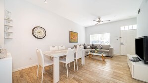 Un salon moderne comprenant une table à manger, un canapé, un téléviseur et des œuvres d’art accrochées au mur.
