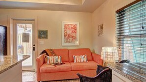 A living room with a sofa, a chair, a table, and a window with blinds.