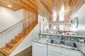 Une cuisine moderne avec un plancher en bois, un comptoir en granit et un évier en acier inoxydable.