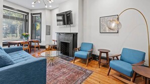 Una sala de estar moderna con chimenea, sofás azules, una mesa de centro y una lámpara de pie grande.