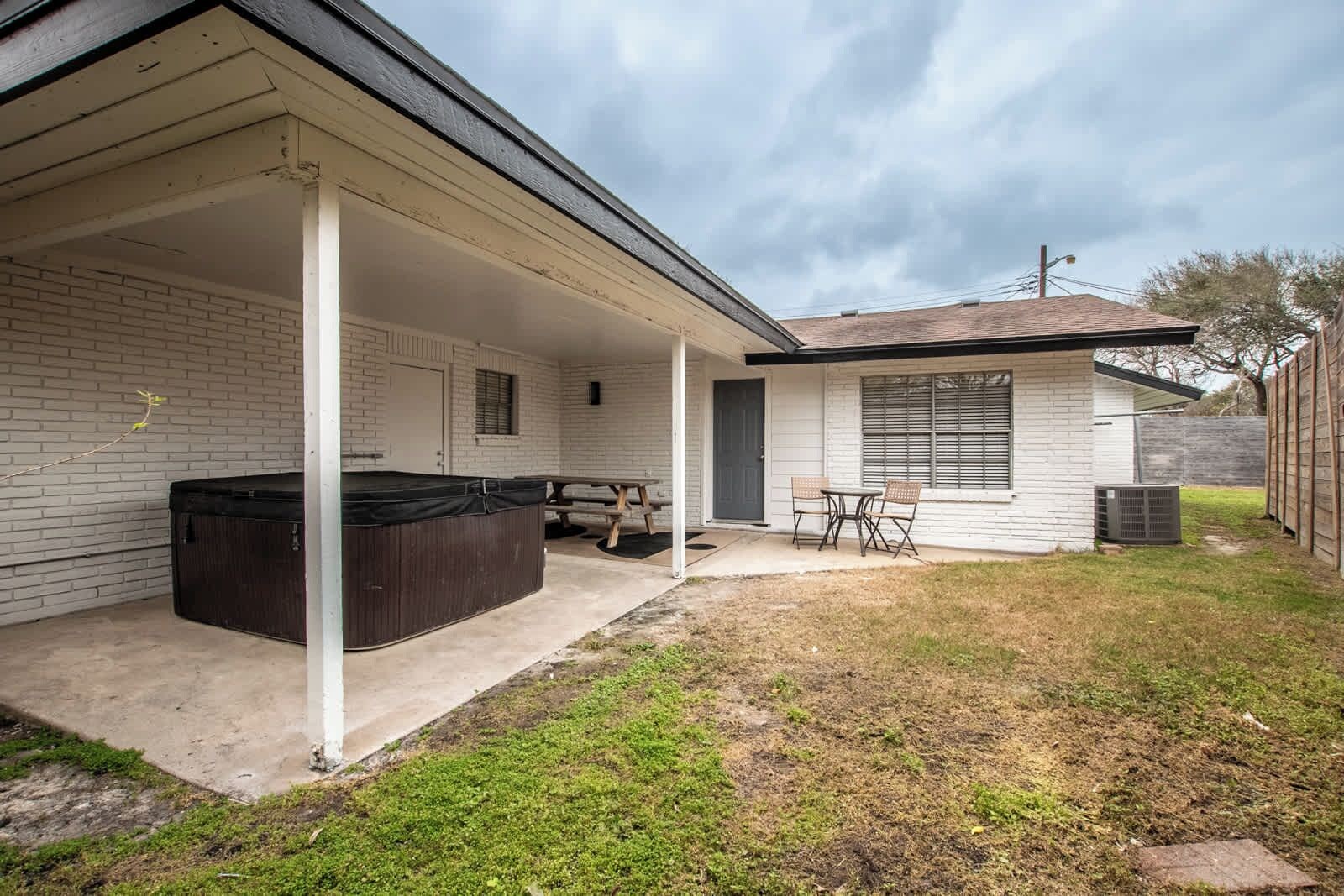 Un área de patio techada con un jacuzzi, una mesa de picnic y sillas.