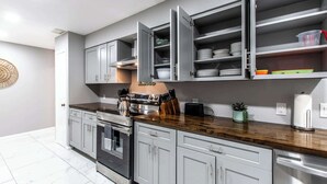A modern kitchen with grey cabinets, a stainless steel stove, and a wooden countertop.