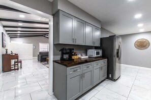 Una cocina moderna con armarios grises, un refrigerador de acero inoxidable y una cafetera.