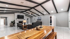 A spacious living room with a wooden dining table, sofas, and a fireplace. - Sleep 29 - Oceanfront Retreat 2 Homes for 29-Guests! (Corpus Christi)