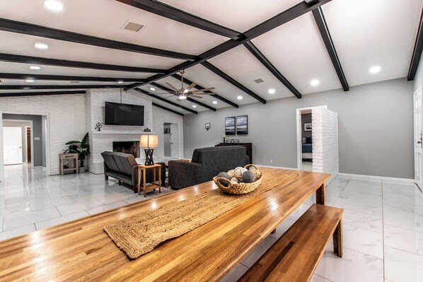 Un salón amplio con una mesa de comedor de madera, sofás y una chimenea.