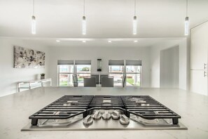 A modern kitchen with a central gas stove, pendant lighting, and a view of the outdoors.