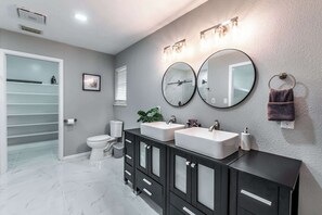 Un baño moderno con dos lavamanos, inodoro y zona de ducha.