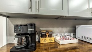 A coffee bar setup with a Keurig coffee maker, jars of coffee, and a coffee mug on a wooden countertop. - Sleep 29 - Oceanfront Retreat 2 Homes for 29-Guests! (Corpus Christi)