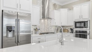 Una cocina moderna con armarios blancos, electrodomésticos de acero inoxidable y una isla central.