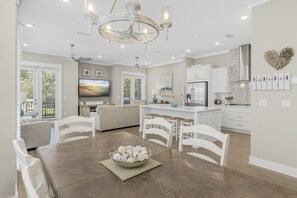 Enjoy meals in this well-equipped kitchen with a central island, stainless steel range hood, and large flat-screen TV.