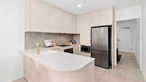 Een moderne keuken met een centraal eiland, roestvrijstalen apparatuur en lichtkleurige kastjes.