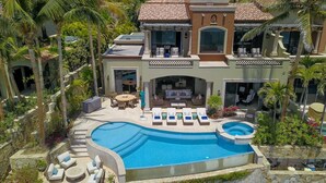 A large house with a swimming pool, outdoor seating, and palm trees. - 5BR Luxury Home in Villas del Mar (Los Cabos)