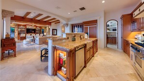 A spacious kitchen with a central island, wooden cabinetry, and a dining area with a sofa and chairs. - 5BR Luxury Home in Villas del Mar (Los Cabos)