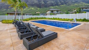 Un espace piscine doté de chaises longues, d’une piscine et offrant une vue sur un paysage montagneux.