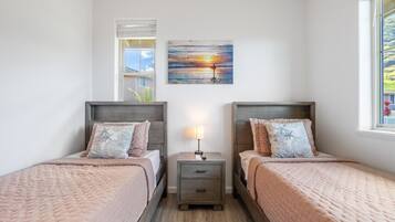 A bedroom with two beds, a nightstand, a lamp, and a painting on the wall.
