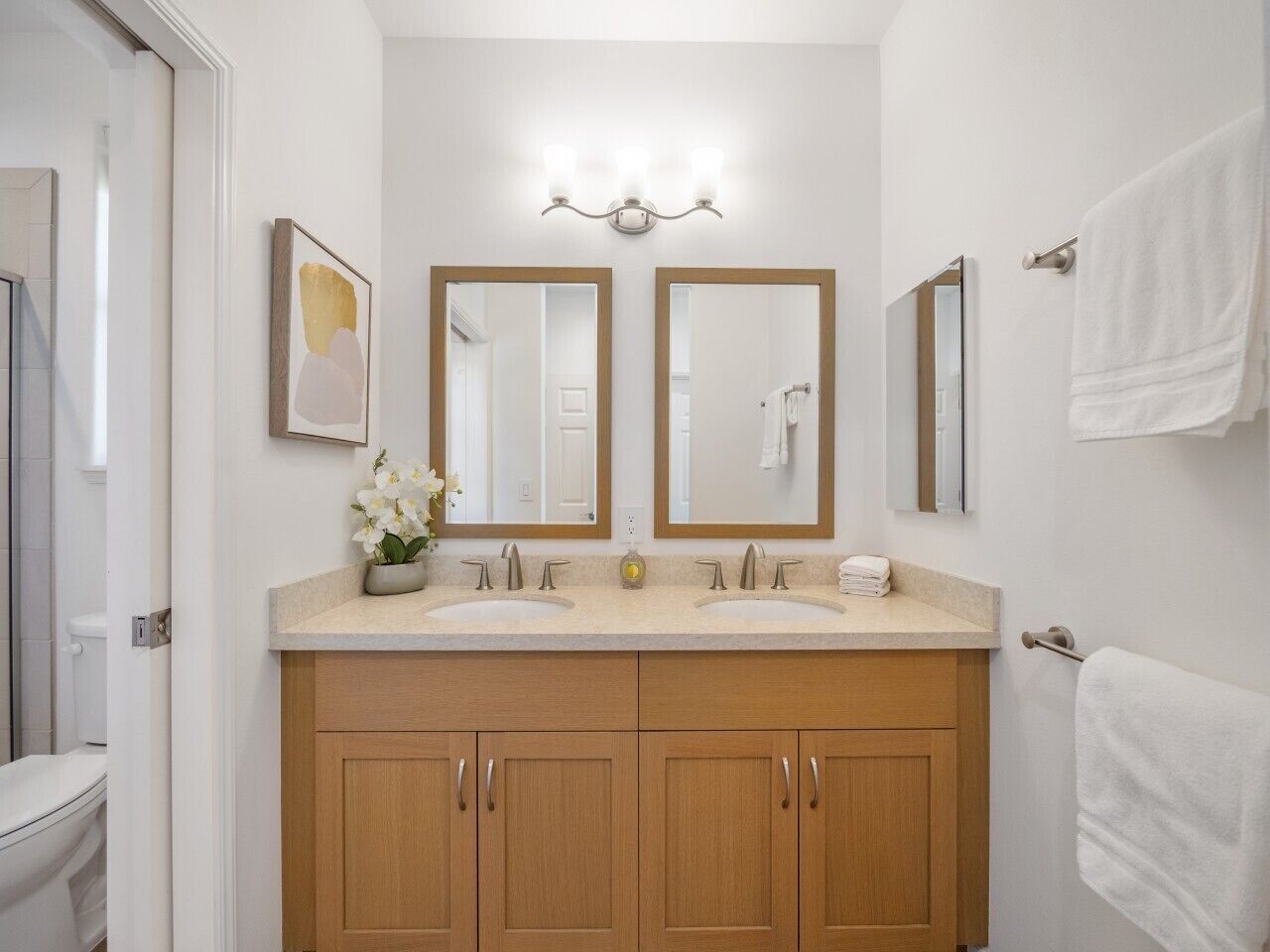 A bathroom with two sinks, wooden cabinets, a mirror, and a light fixture.