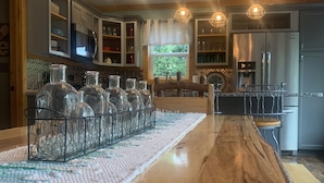 A kitchen with a long wooden island, hanging pendant lights, and built-in cabinets. - Blue Sky Relaxation Retreat! (Gatlinburg)