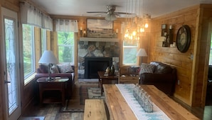 A cozy cabin interior with a stone fireplace, wooden furniture, and a large dining table. - Blue Sky Relaxation Retreat! (Gatlinburg)