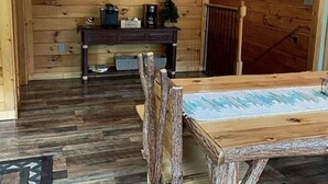 A rustic wooden interior with a dining table and chairs, a wall-mounted coffee machine, and a sign that reads "be our guest." - Blue Sky Relaxation Retreat! (Gatlinburg)