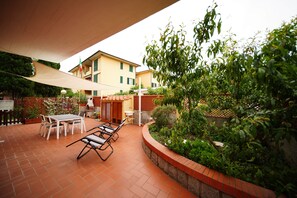 An outdoor patio with a table and chairs, surrounded by greenery and a brick border. - The Lemon House, just a stone's throw from the ocean (campo nell'elba)