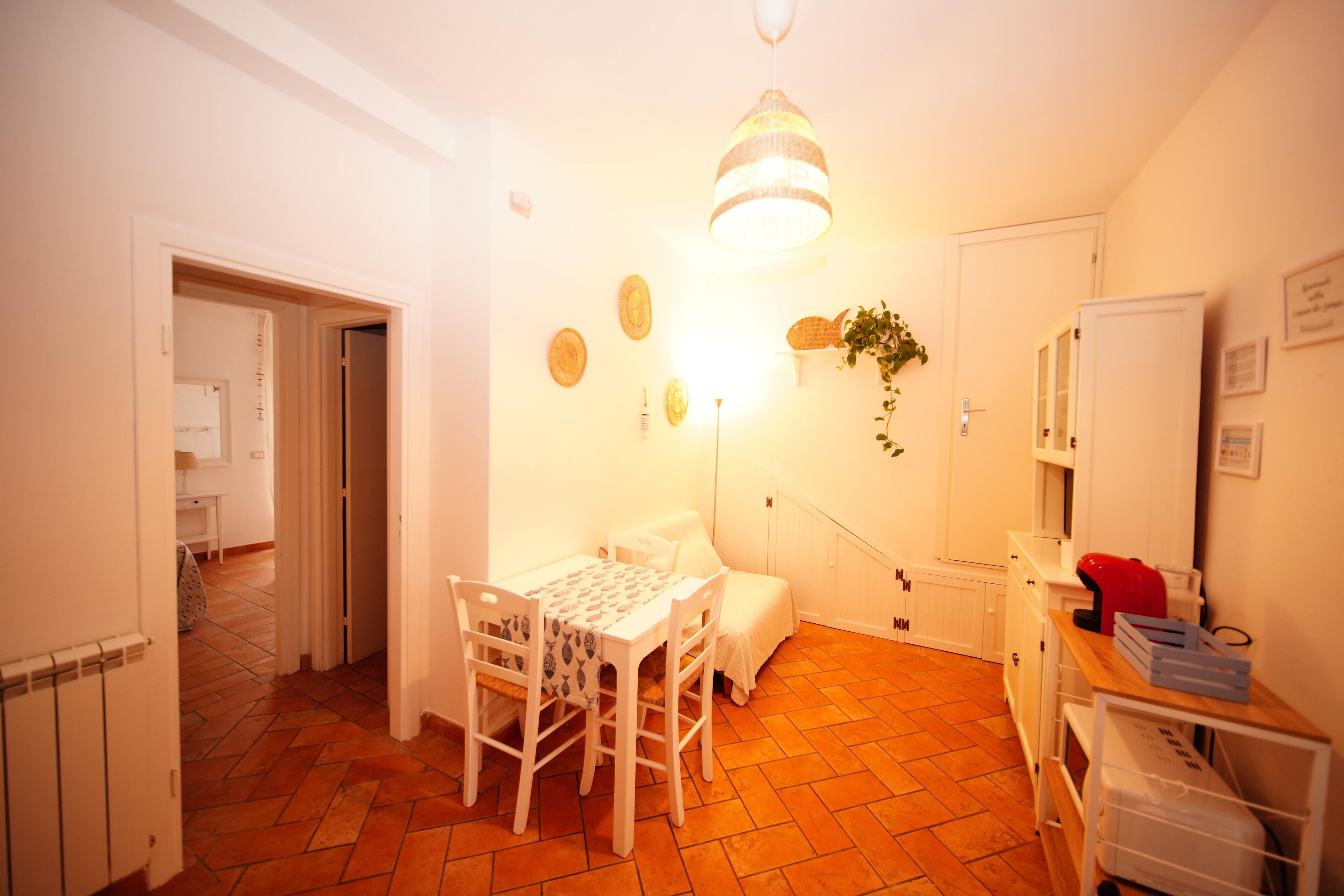 Una cucina compatta con un tavolo da pranzo, sedie e una lampada a sospensione.
