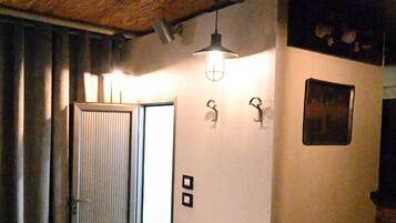 A room with a wooden ceiling, a sliding door, and a light fixture on the wall.