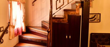 A wooden staircase with a decorative railing, a wooden door with a handle, and a wall-mounted light fixture.